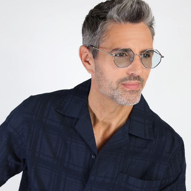 Model with salt and pepper hair and beard looking left wearing Broome Sunglasses Silver with Light Blue Flat See Through