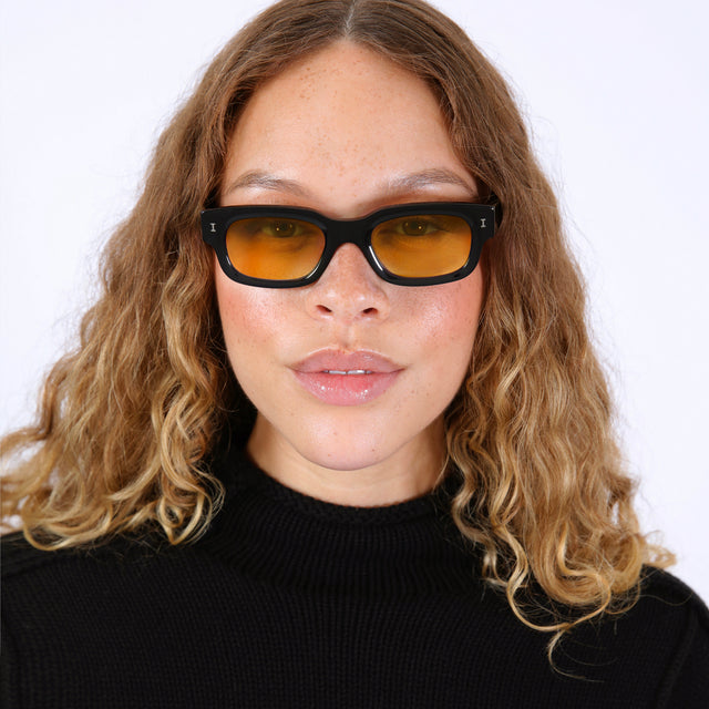 Brunette model with wavy ombre wearing Cali Sunglasses Black with Honey See Through