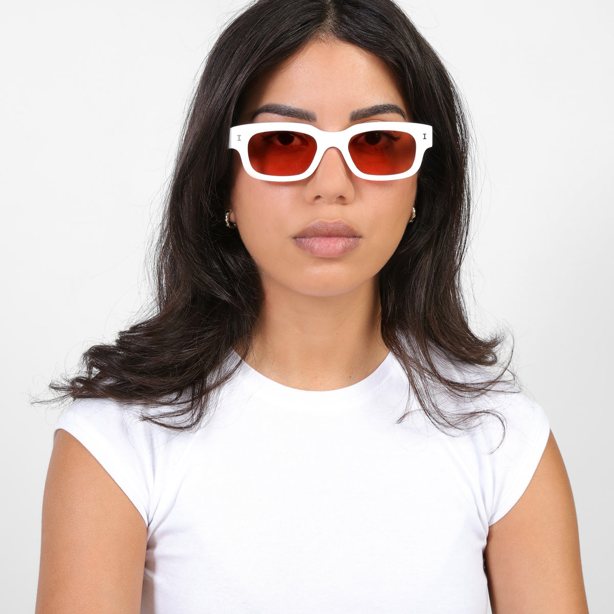 Woman wearing Cali E Sunglasses in White with Guava See Through lenses, Brunette model in a white tee