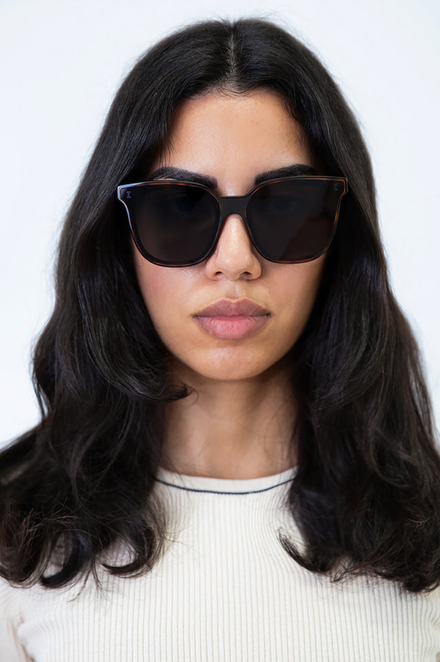 Brunette model with wavy hair wearing Camille 64 Sunglasses Havana with Grey Flat