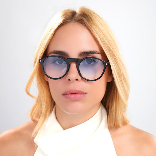 Blond woman in white silk blouse wearing Capri Sunglasses Black with Blue Gradient See Through