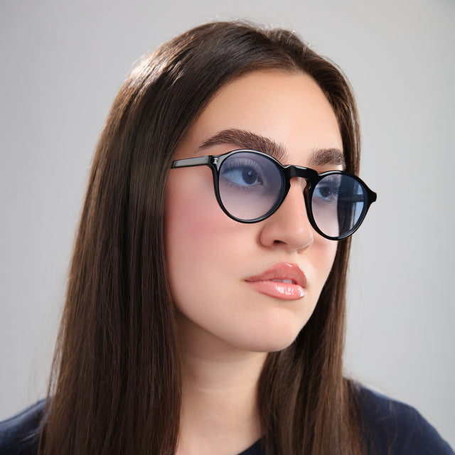 Brunette model looking left wearing Capri Sunglasses Black with Blue Gradient See Through