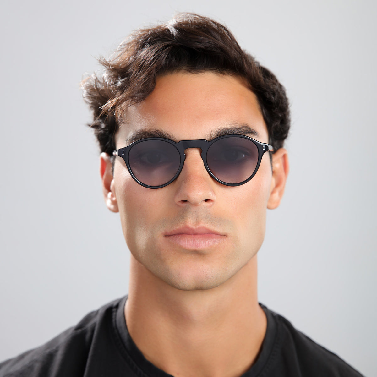 Man wearing Capri Sunglasses in Black with Grey Gradient lenses, front view, Man in black tee