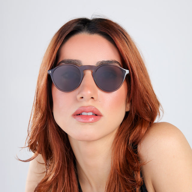 Woman with red hair in a black blouse wearing Capri Sunglasses Mercury with Grey
