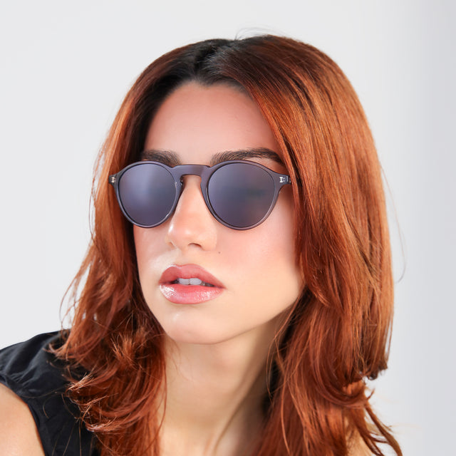 Woman with red hair in a black blouse looking to her right wearing Capri Sunglasses Mercury with Grey