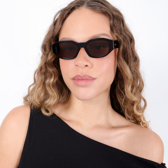 Brunette model with ombré, natural curls wearing Cassette Sunglasses Black with Brown Flat