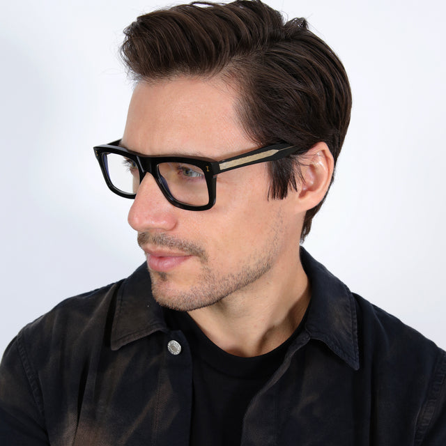 Model with short brown hair in a black collared shirt wearing Catania Optical Black/Gold Optical