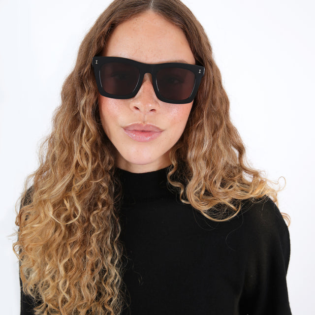 Brunette model with ombré, natural curls  wearing Charleston Sunglasses Black with Grey Flat