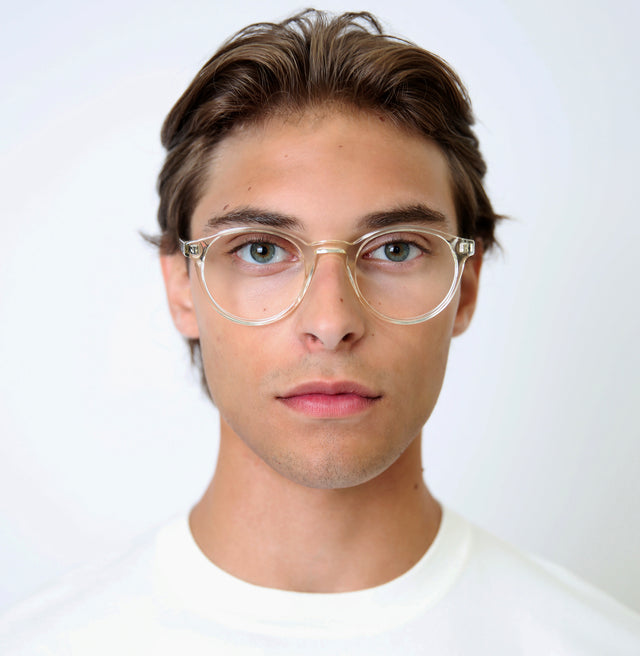 Model with slicked back brown hair wearing Como Optical Champagne Optical
