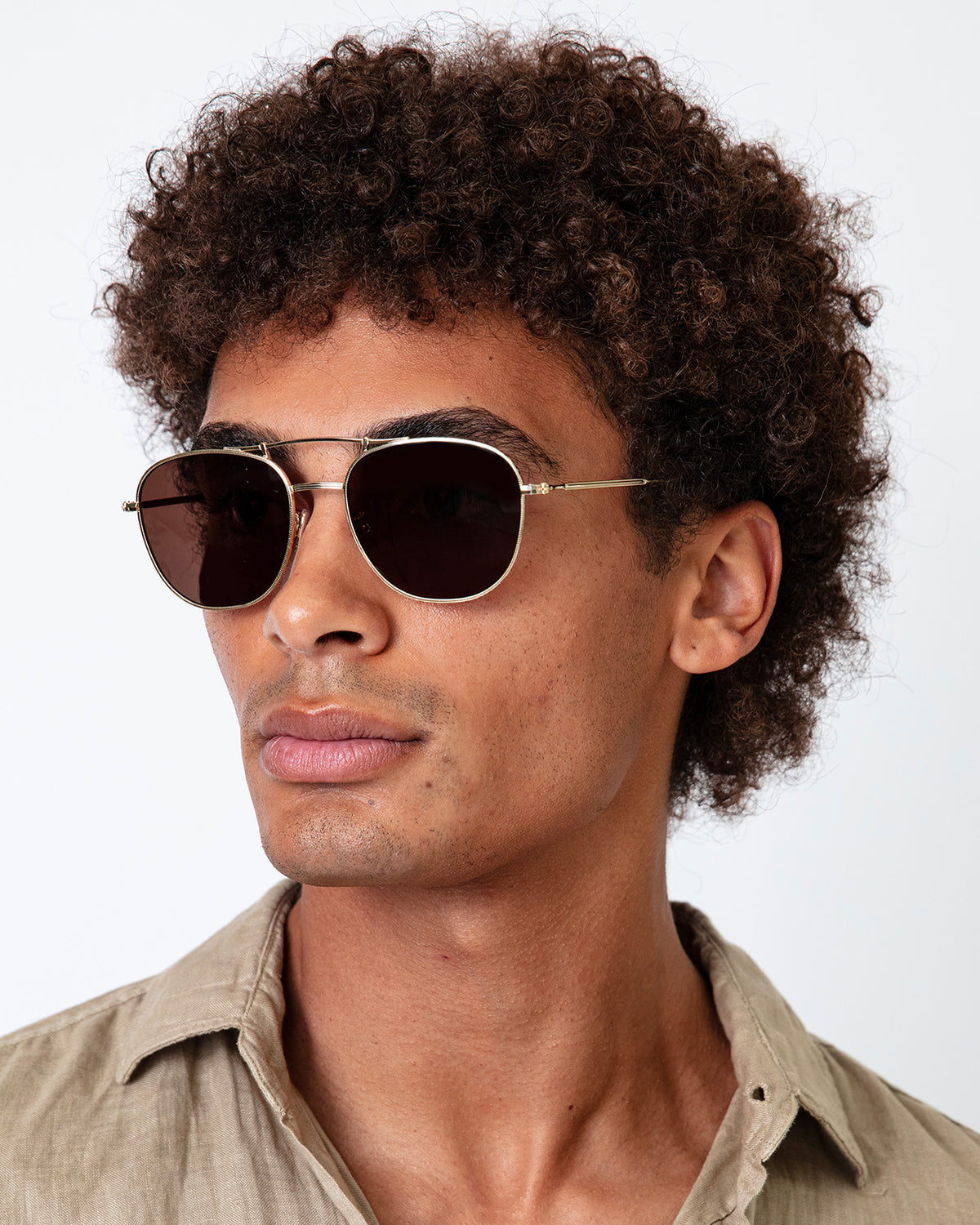 Man wearing Cyprus Sunglasses in Gold with Brown Flat lenses, Model with afro-curly hair