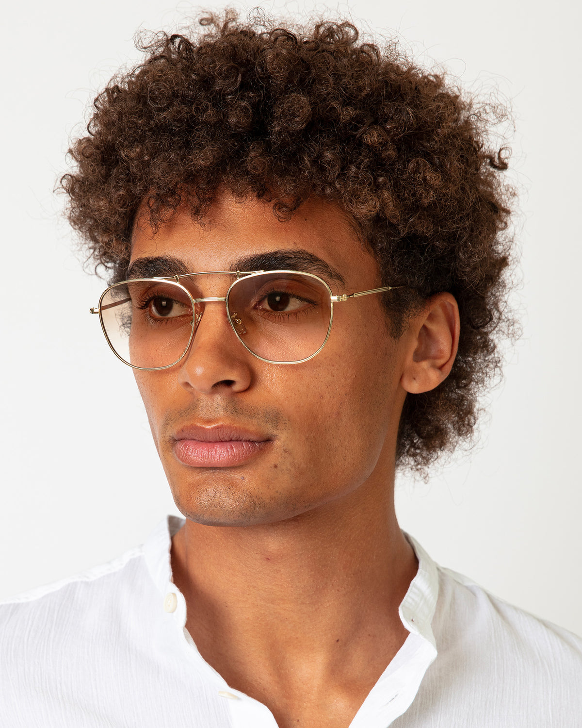 Man wearing Cyprus Sunglasses in Gold with Taupe Flat Gradient lenses, Model with afro-curly hair