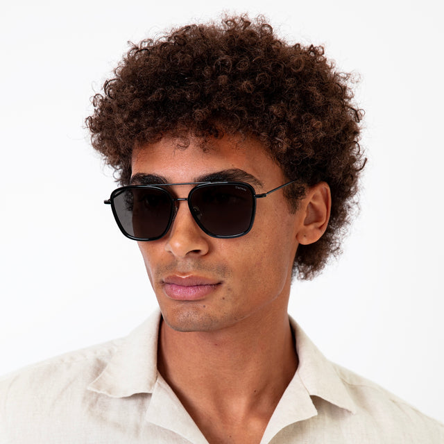 Model with afro-curly hair wearing Delos Ace Sunglasses Black with Grey Flat