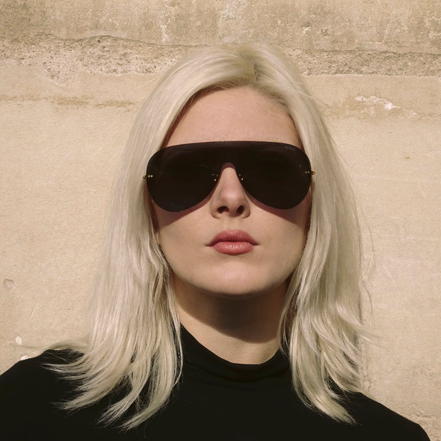 Another angle of woman in Paris leaning against a wall wearing Douglas Mask Sunglasses Grey with Grey