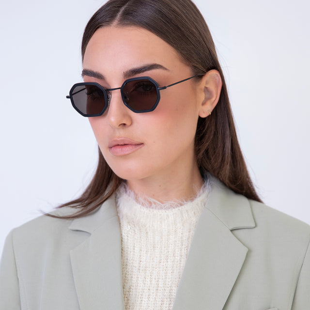 Brunette model with straight hair in a blazer wearing Dylan Tate Sunglasses Matte Black with Grey Flat Lenses
