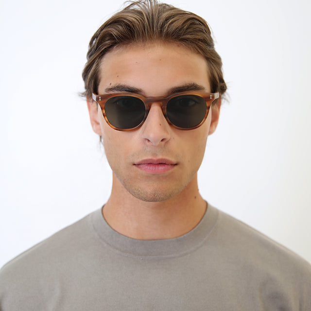 Model with light brown hair combed back wearing Eldridge 48 Light Sunglasses Matte Teak with Olive Flat