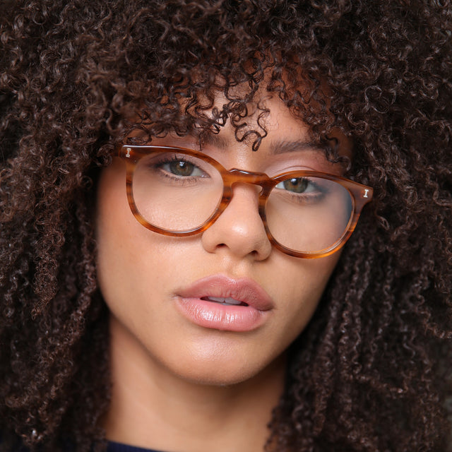 Brunette model with afro-curly hair wearing Eldridge 48 Optical Teak Optical