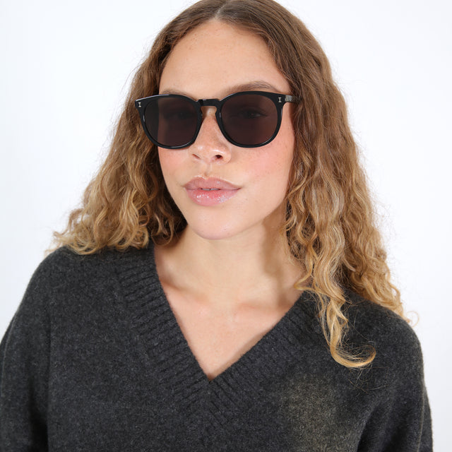 Brunette model with ombré natural curls wearing Eldridge 56 Sunglasses Black with Grey Flat