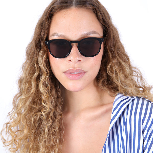 Brunette model with ombre, natural curls wearing Eldridge Sunglasses Black with Brown Flat