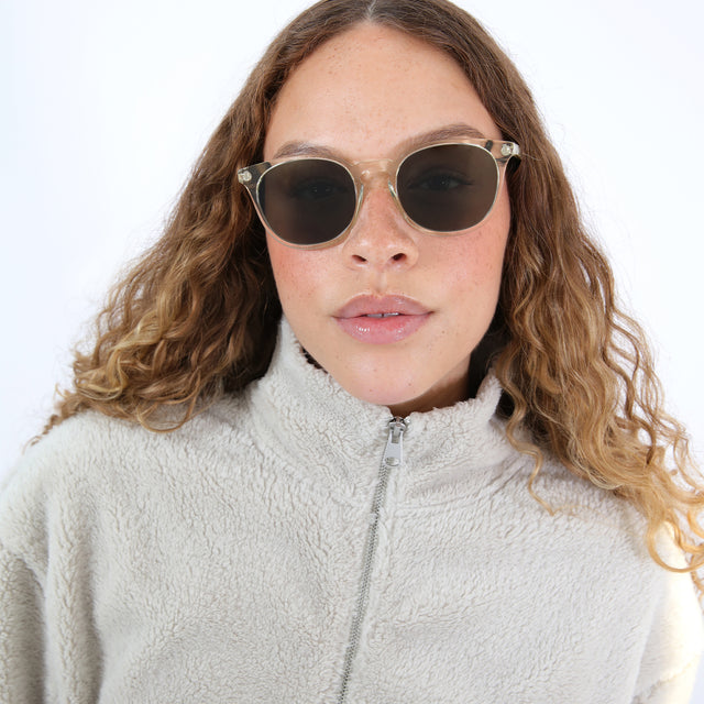 Brunette model with ombre, natural curls wearing Eldridge Sunglasses Champagne with Olive Flat