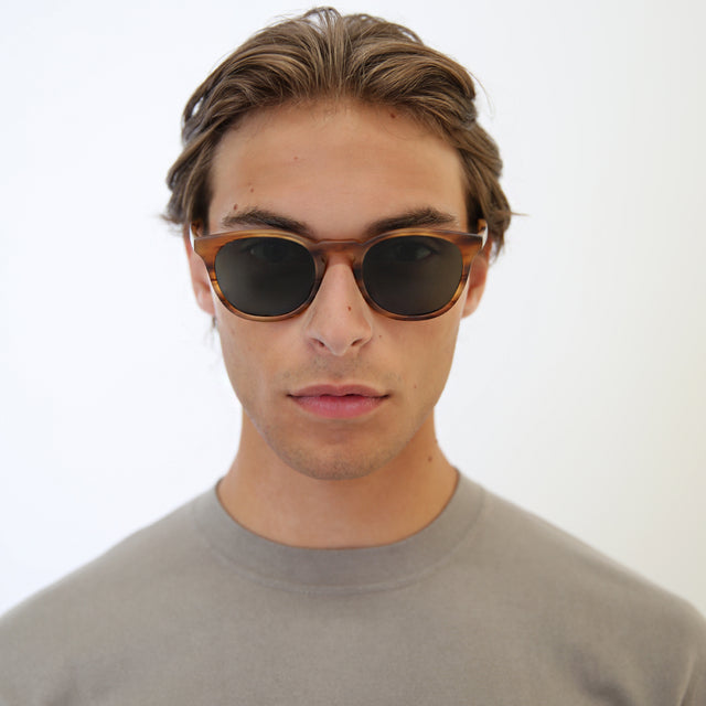 Model with light brown hair combed back wearing Eldridge Light Sunglasses Matte Teak with Olive Flat