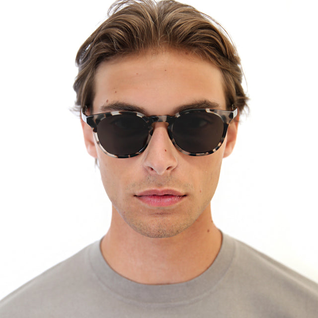 Model with light brown hair combed back wearing Eldridge Light Sunglasses White Tortoise with Grey Flat