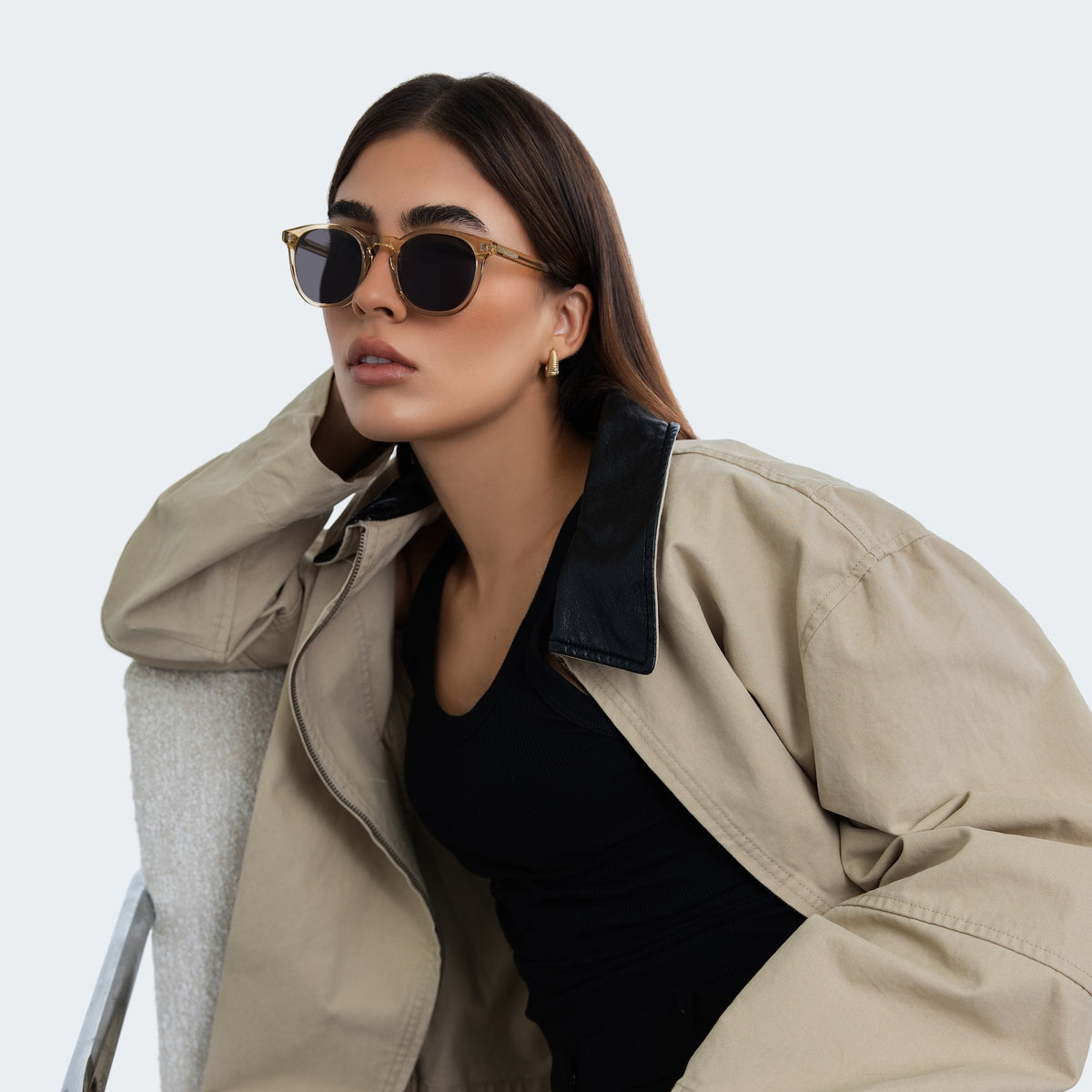 Woman wearing Eldridge 56 Sunglasses in Citrine with Grey Flat lenses, side profile, Woman in a trench coat leaning on studio chair