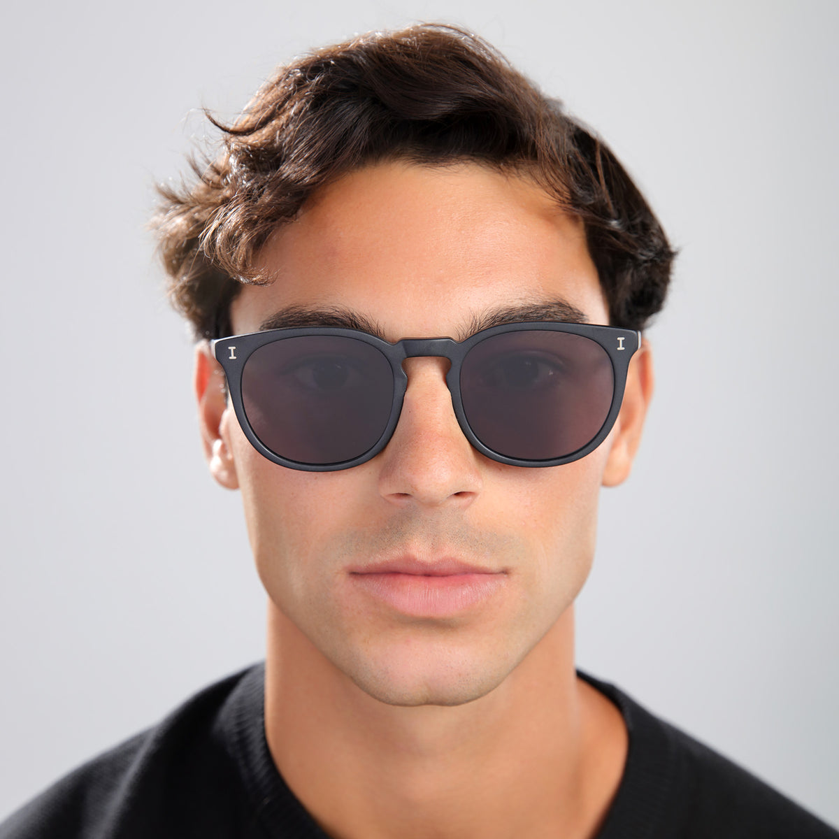 Man wearing Eldridge 56 Sunglasses in Matte Black with Grey Flat lenses, front view, Man with brown hair in a black tee
