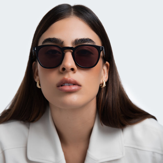 Woman in a white blazer wearing Eldridge Sunglasses Black with Plum Flat See Through