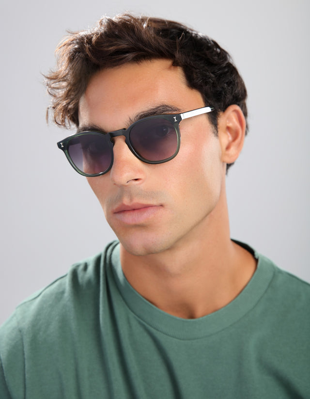 Man wearing Eldridge sunglasses and a green shirt against a gray background
