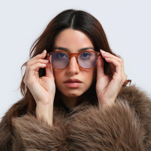 Woman in a faux fur coat wearing Eldridge Sunglasses Toffee with Light Blue Flat See Through