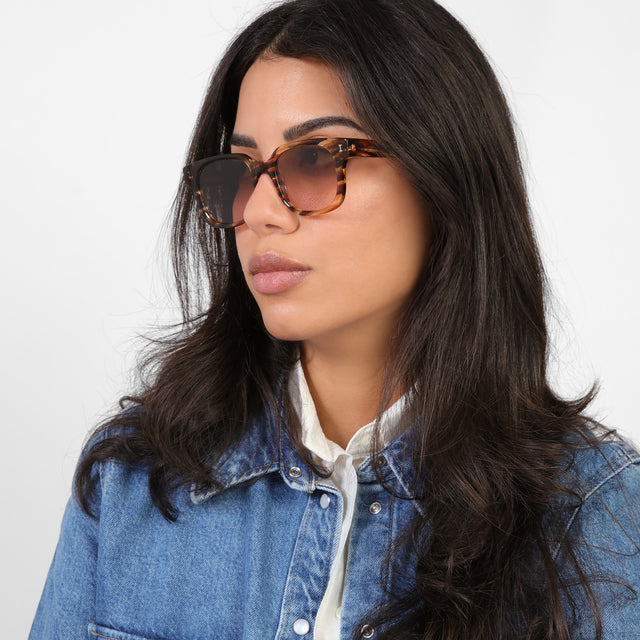 Brunette model in a denim jacket looking right wearing Ellison Sunglasses Sand Dune with Brown Flat Gradient