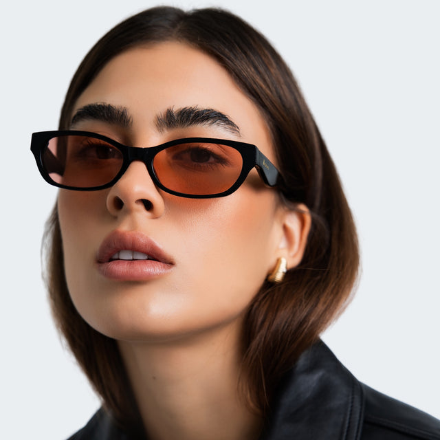 Woman in a black leather blouse wearing Encinitas Sunglasses Black with Sunset