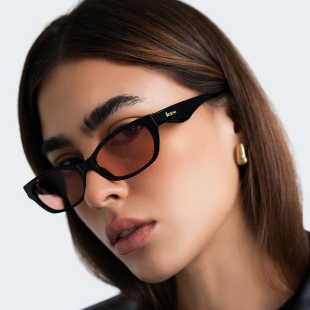 Close up of woman in a black leather blouse wearing Encinitas Sunglasses Black with Sunset