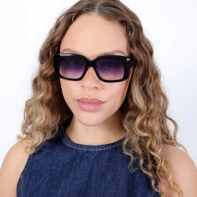 Brunette model with ombré, natural curls wearing Geno Sunglasses Black with Purple Gradient