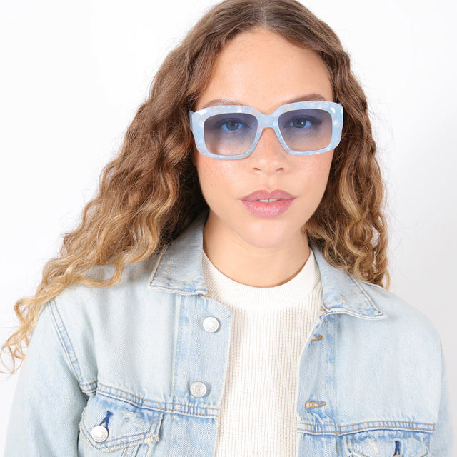 Brunette model with ombré, natural curls wearing Geno Sunglasses Celeste with Blue Gradient See Through