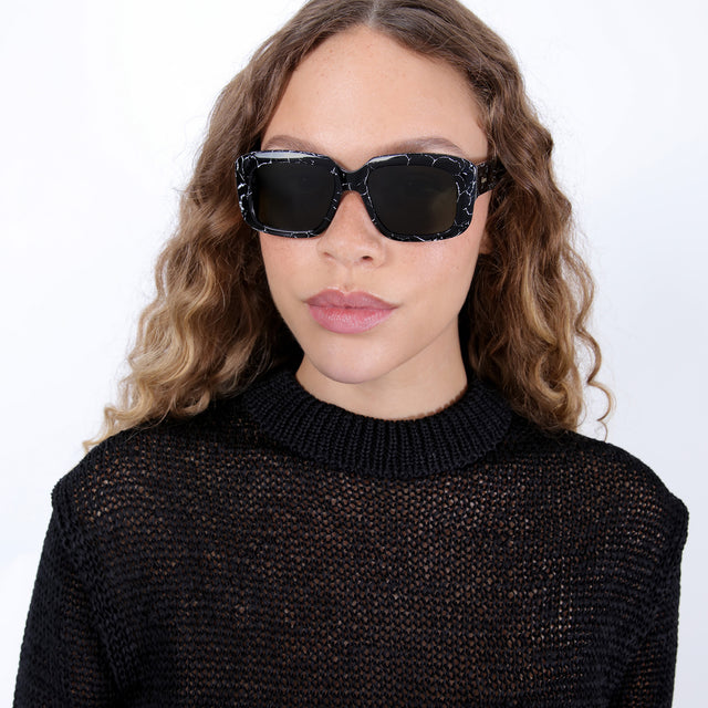 Brunette model with ombré, natural curls wearing Geno Sunglasses Obsidian with Olive