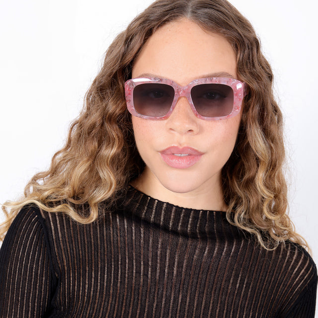Brunette model with ombré, natural curls wearing Geno Sunglasses Rose Quartz with Grey Gradient