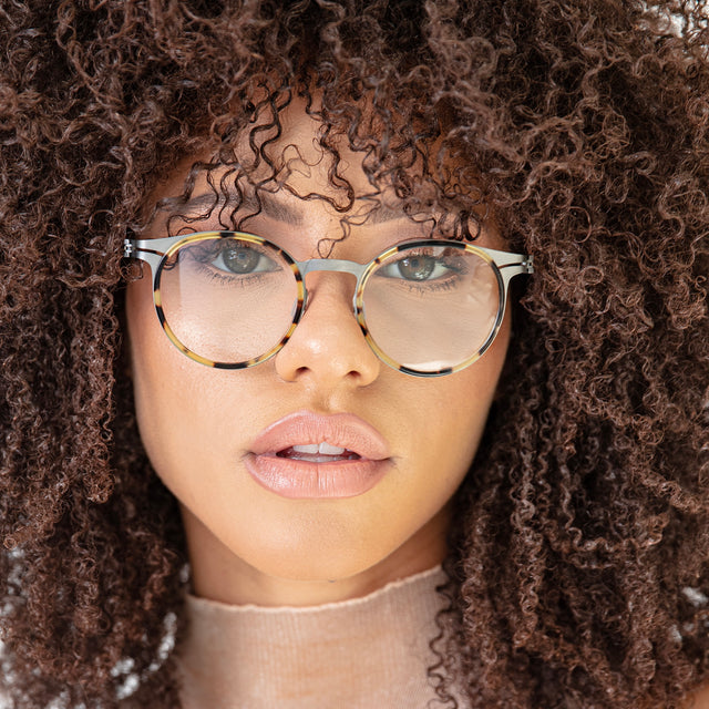 Brunette model with afro-curly hair wearing Great Jones Titanium Optical Tortoise/Matte Silver Optical