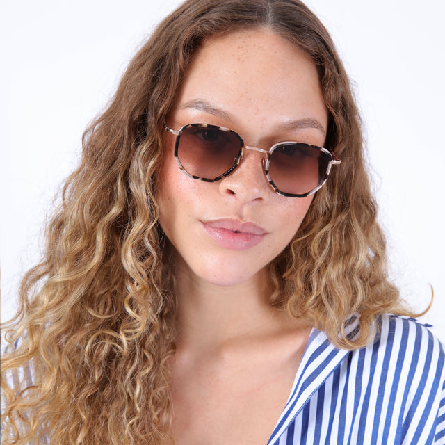 Brunette model with wavy hair in a striped blouse wearing Hunter Ace Sunglasses White Tortoise/Rose Gold with Brown Gradient