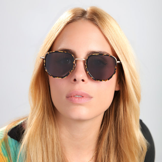 Blond woman in a multiwearing ed sweatshirt wearing Hunter Ace Sunglasses Flame/Gold with Grey