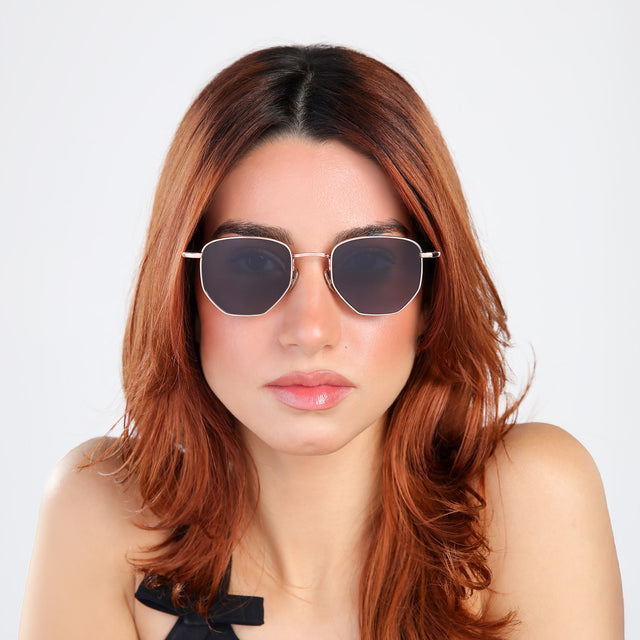 Woman with red hair in a black blouse wearing Hunter Sunglasses Rose Gold with Grey
