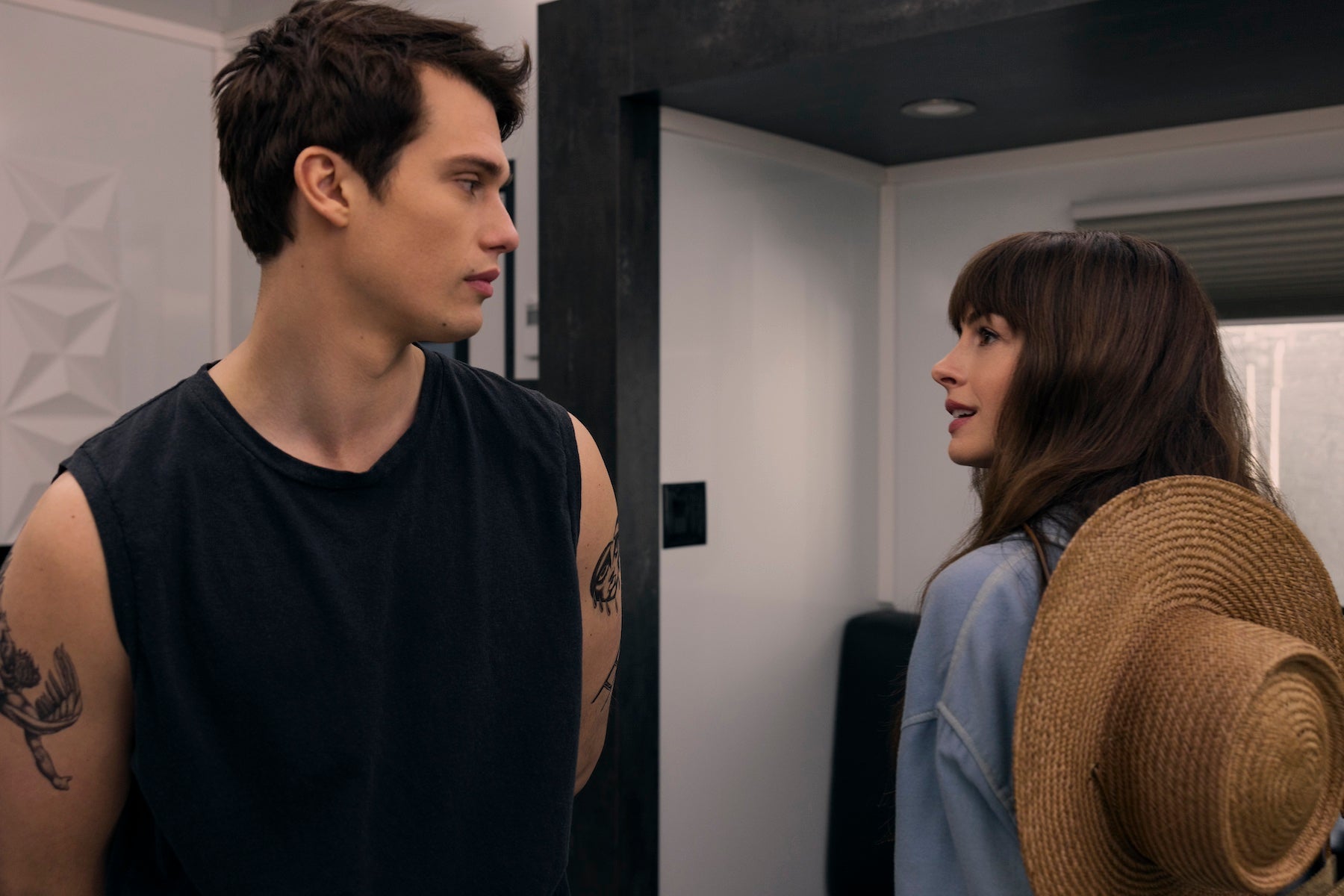 Still from 'The Idea of You' featuring Anne Hathaway and Nicholas Galitzine gazing at each other in a hallway