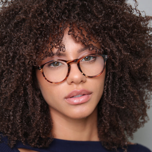 Brunette model with afro-curly hair wearing Lawrence Optical Sand Dune Optical