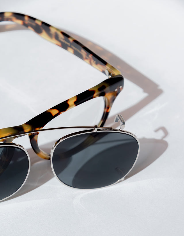 Lenox in tortoiseshell frame and dark lens clip on on a light background