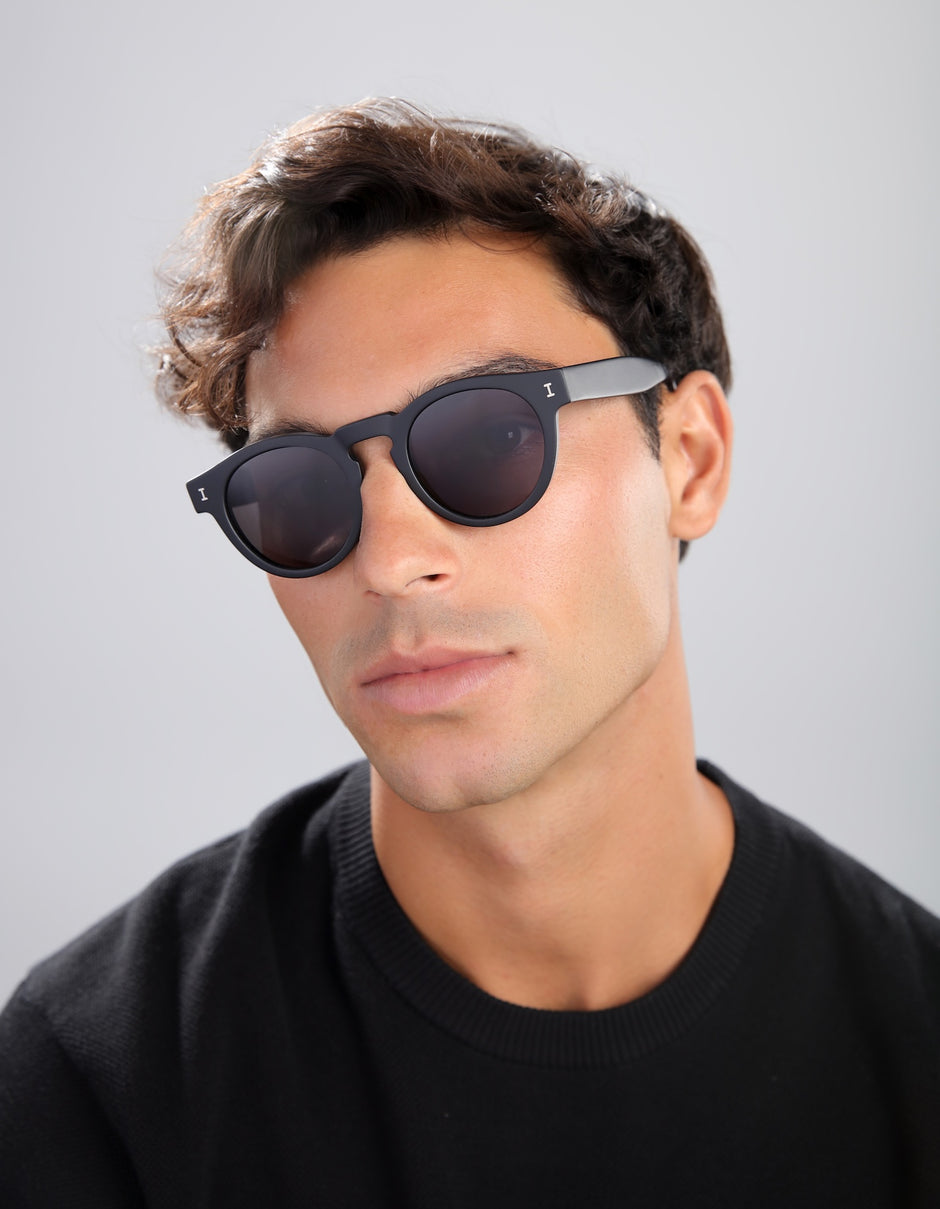 Man in a black tee wearing the Leonard Matte Black with polarized grey lenses