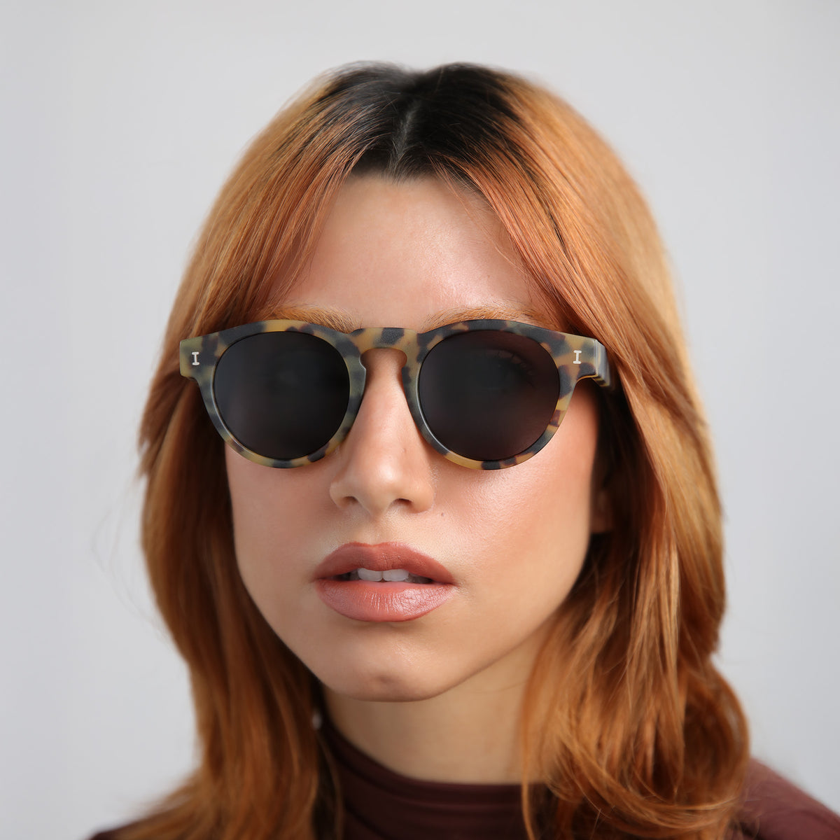 Woman wearing Leonard Polarized Sunglasses in Matte Tortoise with Grey Polarized lenses, Woman with red hair in a mockneck blouse