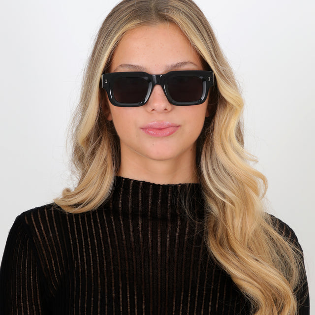 Blonde model with loose curls wearing Lewis Sunglasses Black with Grey Flat