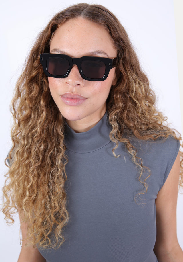 Brunette model with ombre curls wearing Lewis 50 Sunglasses in Black with Grey
