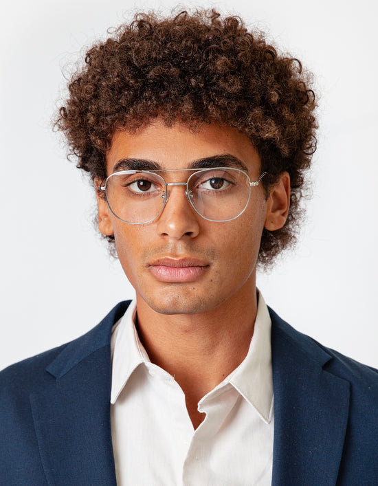 Model with short, natural curls wearing a navy suit with Limassol Optical in Silver
