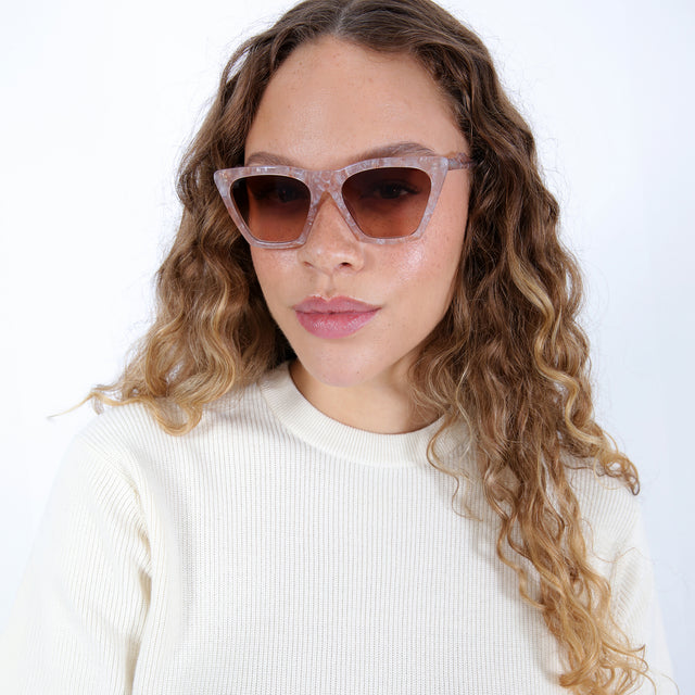 Brunette model with ombré, natural curls wearing Lisbon Sunglasses Cashmere with Brown Gradient